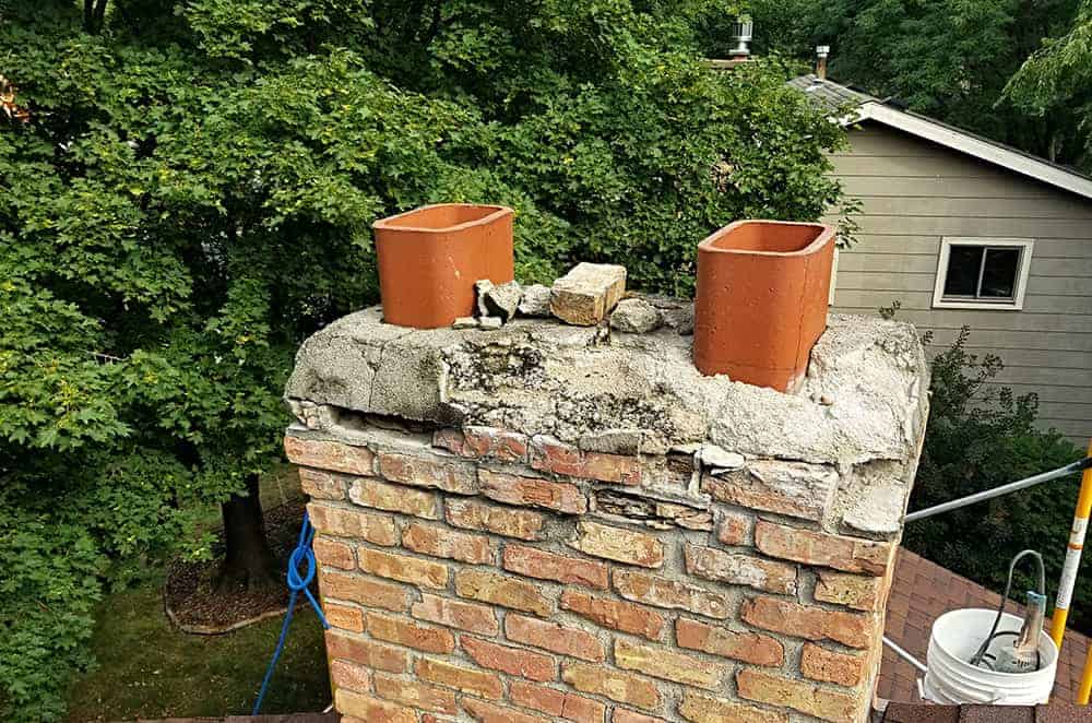deteriorating chimney on roof in suburban neighborhood.