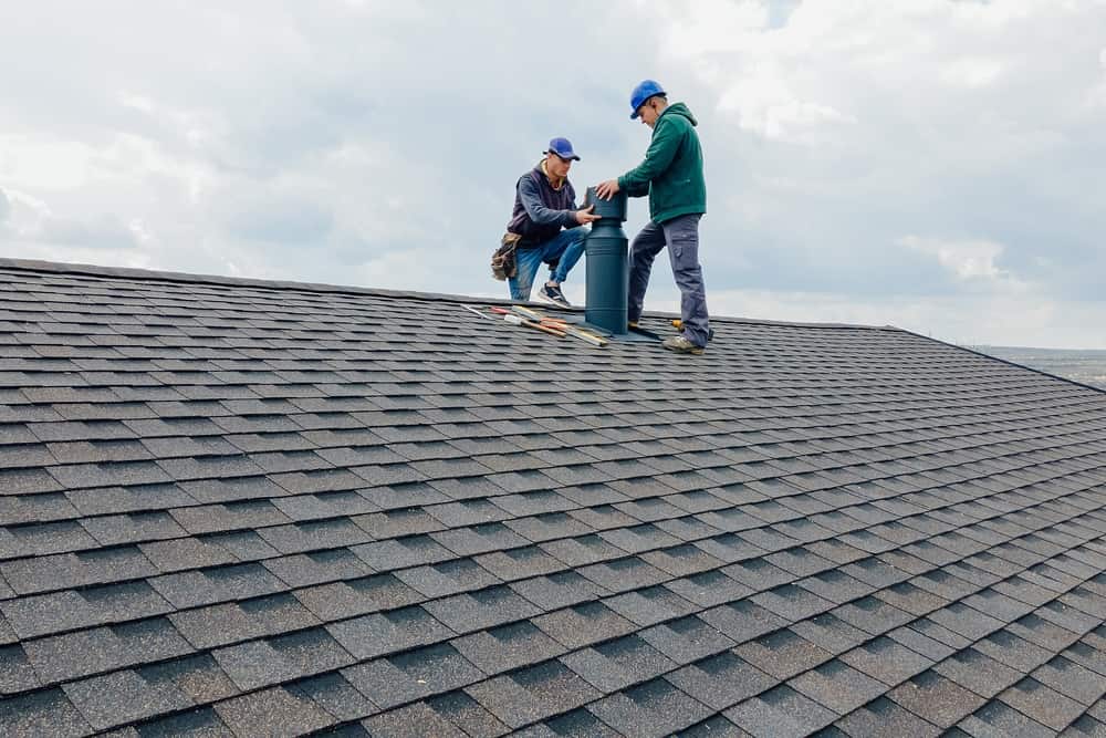 Construction workers Installing chimney and building construction concept. Contractor Builder with blue hardhat on the roof caulking chimney